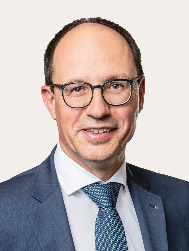 Ein Foto von Marc Mächler vor beigem Hintergrund.