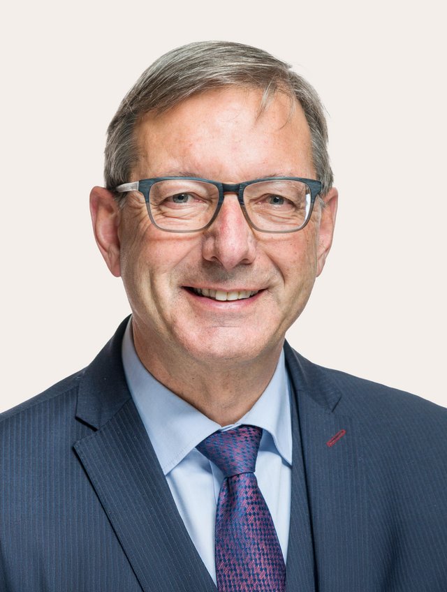 Ein Foto von Josef Dittli vor beigem Hintergrund